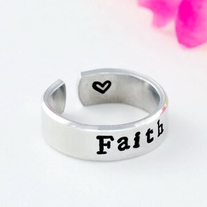 May include: Silver adjustable ring with the word "Faith" engraved on the outside and a small heart on the inside.