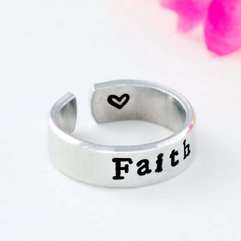 May include: Silver adjustable ring with the word "Faith" engraved on the outside and a small heart on the inside.