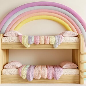 Puede incluir: Una litera de madera con un arco de colores de arcoíris detrás. La cama tiene una manta y almohadas con estampado blanco y rosa.