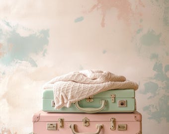 May include: Three vintage suitcases stacked on top of each other. The top suitcase is light green, the middle suitcase is pink, and the bottom suitcase is light green. The suitcases have metal clasps and handles.