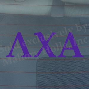 May include: Purple vinyl decal with the letters AXA. The decal is on a car window.