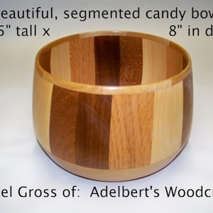 May include: A segmented wooden candy bowl with a natural wood finish. The bowl is 5 inches tall and 8 inches in diameter. It is made of different types of wood, creating a unique and beautiful pattern.