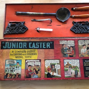 May include: Vintage "Junior Caster" metal toy casting kit. The open box reveals a ladle, molds, and other tools. The box features comic-style illustrations and text, including "A COMPLETE OUTFIT for CASTING and COLORING METAL TOYS!"