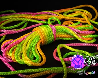 May include: A close-up of a multi-colored rope made of three colors: pink, yellow, and green. The rope is twisted and knotted, creating a visually appealing texture. The rope is a popular choice for crafts, hobbies, and decorative purposes.