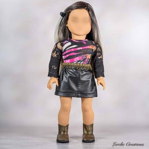 May include: A doll with long straight hair featuring dark roots and light ends. The doll wears a long-sleeved top with black lace sleeves and a pink, black, and white patterned bodice, a black faux leather skirt with gold fringe, and bronze boots.