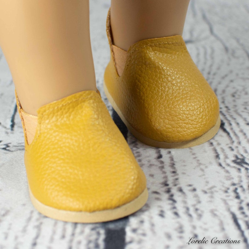 Puede incluir: Un par de zapatos amarillos mostaza de vestir con acabado de cuero texturizado. Los zapatos tienen una punta redonda y un dise&ntilde;o sencillo.
