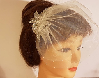 May include: A white bridal veil with a beaded edge and a floral embellishment with rhinestones.