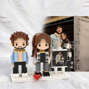May include: A personalized Lego-style figurine set featuring a couple, with a red heart and a photo of the couple. The male figure wears a light blue jacket, and the female figure wears a black and white plaid shirt.