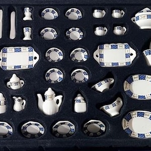 May include: A white ceramic mug with a black handle and the text "But First, Coffee" in a black, bold font. The mug is on a white surface.