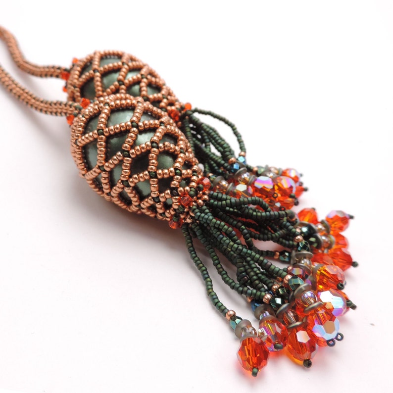 May include: A copper and green beaded necklace with a tassel of orange and green beads.