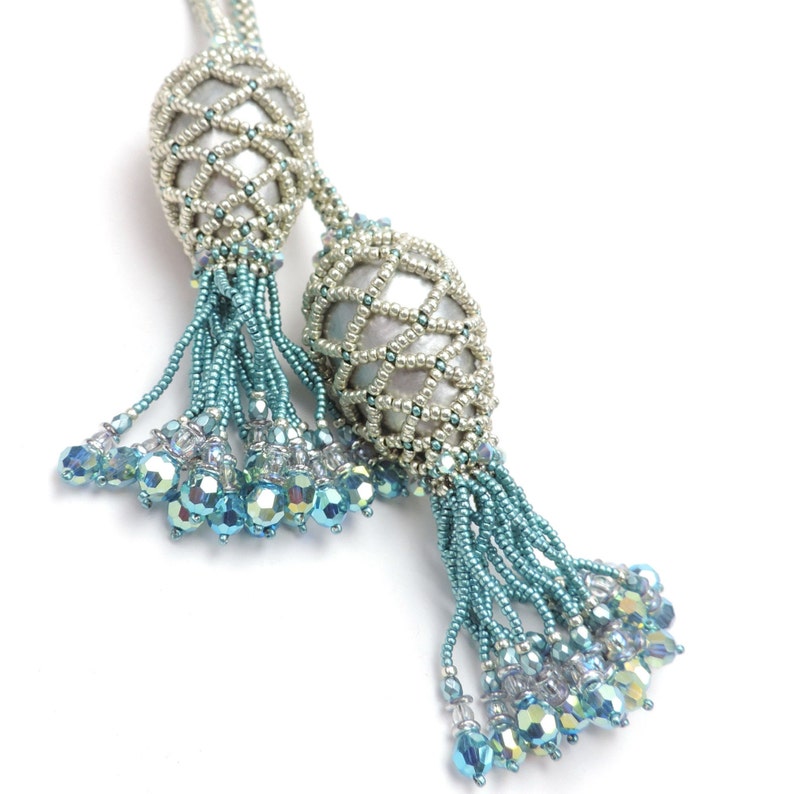 May include: Two beaded tassels with silver and white beads, each with a blue and silver beaded fringe.