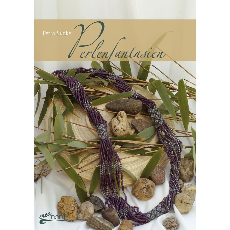 May include: A book titled "Perlenfantasien" by Petra Sudke, featuring a close-up of a purple and blue beaded necklace on a wooden surface with green leaves and stones.