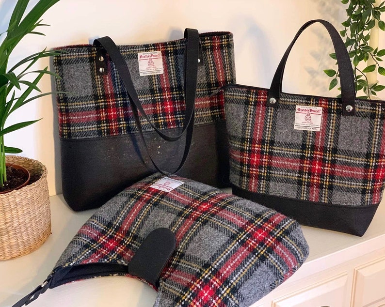 May include: Three gray and red plaid tote bags with black leather handles and black bottoms. The bags have a label that says "Harris Tweed" on them.
