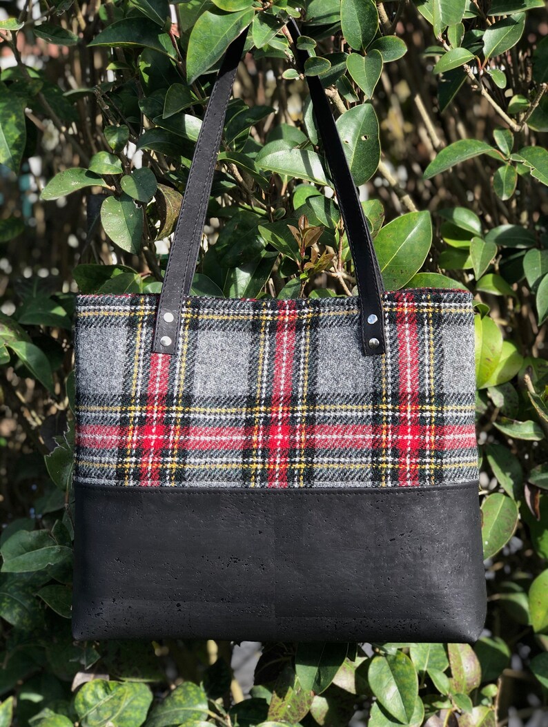 May include: A black and gray plaid tote bag with a black leather bottom. The bag has black leather straps.