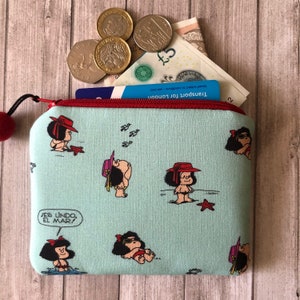 Op de afbeelding: Een lichtblauwe ritszak met een rode rits. De tas is versierd met een herhalend patroon van cartoonfiguren die rode hoeden en badpakken dragen. De tekst "ES LINDO, EL MAR!" is op de tas gedrukt.