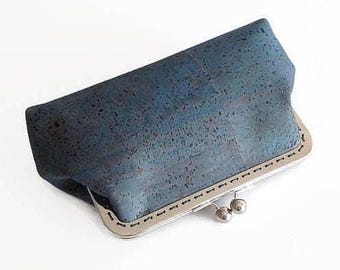 Pode incluir: Uma carteira de mão de cortiça azul com moldura e fecho prateados.