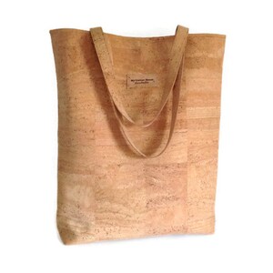 May include: A light brown cork tote bag with two long straps. The bag has a small label that says "My Cotton House Handmade".