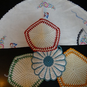 May include: Four crocheted doilies in different colors and patterns. The doilies are white with red, green, blue, and orange accents. The doilies are arranged in a pyramid shape.