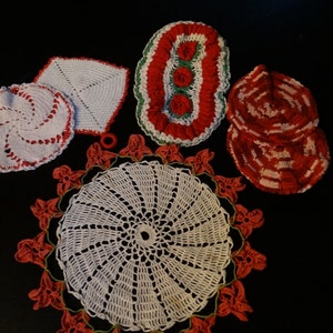 May include: Set of six crocheted pot holders in white and red. The pot holders feature various designs, including a spiral, a square, a flower, and a heart.