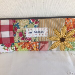 May include: A patchwork fabric zippered pouch with a yellow flower design and the text "MY NEEDLES" on a white label.