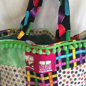 May include: A patchwork tote bag with green pom pom trim. The bag is made of different fabrics, including a green floral print, a pink fabric with a pattern of colorful vans, a black and white fabric with a ruler pattern, and a beige fabric with a pattern of colorful buttons. The bag has two black handles with a colorful geometric pattern.