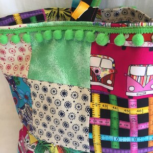 May include: A patchwork tote bag with a green pom-pom trim. The bag is made of different fabrics with various patterns, including flowers, polka dots, and a ruler design. The bag has a black and white fabric handle.