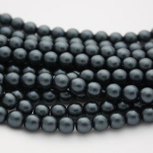 May include: A strand of dark gray pearl beads. The beads are round and smooth, and they have a slightly iridescent finish.