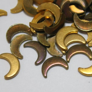 May include: A pile of gold and bronze crescent moon shaped metal charms. The charms have a shiny, iridescent finish.