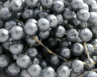 May include: A strand of silver-colored pearl beads, strung on a natural twine thread. The beads are round and smooth, with a slightly iridescent finish.