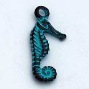 May include: A turquoise blue seahorse charm with a black outline. The charm has a loop at the top for attaching to a necklace or bracelet.