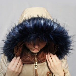 May include: A beige hooded jacket with a dark blue faux fur trim around the hood.