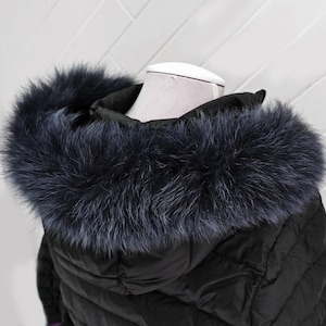 May include: Black puffer jacket with a large, fluffy, dark blue faux fur hood.