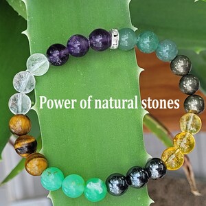 May include: A beaded bracelet featuring a variety of colorful natural stones, including amethyst, green aventurine, and tiger's eye. The bracelet has a silver spacer bead and the text "Power of natural stones".