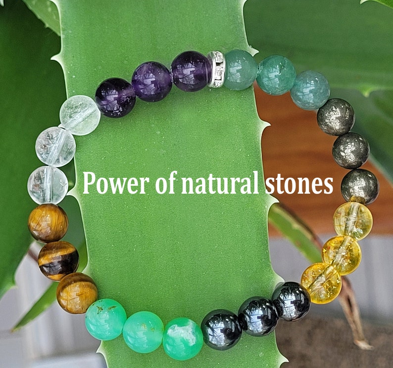 May include: A beaded bracelet featuring a variety of colorful natural stones, including amethyst, green aventurine, and tiger's eye. The bracelet has a silver spacer bead and the text "Power of natural stones".