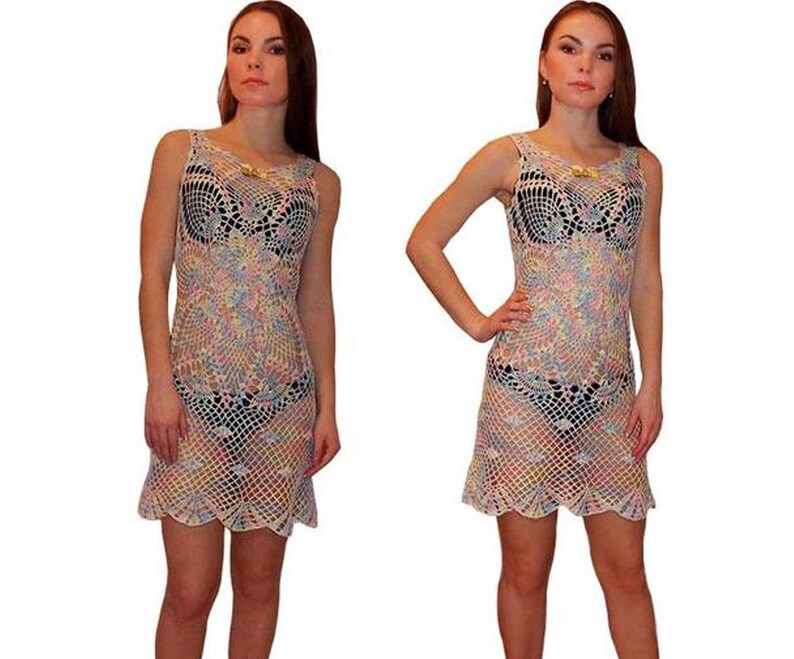 May include: A white crochet dress with a rainbow pattern. The dress has a scoop neck and a scalloped hem.