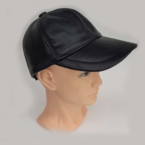 Puede incluir: Una gorra de b&eacute;isbol de cuero negro con visera curva. La gorra se lleva puesta en la cabeza de un maniqu&iacute;.
