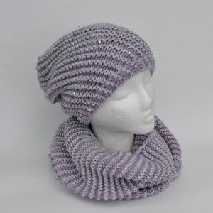 May include: A gray and purple knit beanie with sequins and a matching knit scarf.