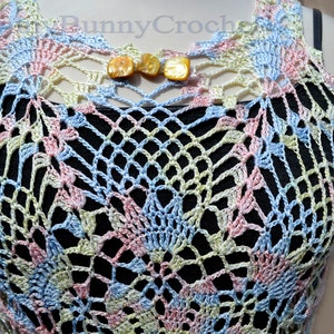 May include: A crocheted top in shades of blue, pink, and green. The top has a delicate, lacy pattern and is sleeveless. It features a small opening at the neckline with two decorative buttons.