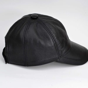 Puede incluir: Una gorra de b&eacute;isbol de cuero negro con visera curva. La gorra tiene un solo bot&oacute;n en la parte superior.