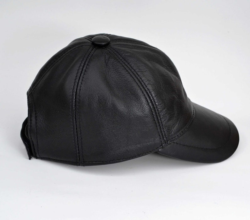 Puede incluir: Una gorra de b&eacute;isbol de cuero negro con visera curva. La gorra tiene un solo bot&oacute;n en la parte superior.