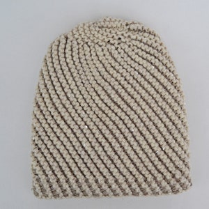 May include: A beige knitted beanie with a diagonal pattern and silver sequins.