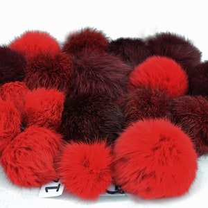 May include: A collection of red and brown faux fur pom-poms. The pom-poms are soft and fluffy and would be perfect for adding a touch of whimsy to any project.