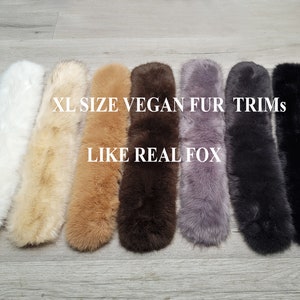 May include: XL Size Vegan Fur Trims, Like Real Fox. Seven faux fur trims in different colors, including white, beige, brown, dark brown, gray, black, and black. The trims are laid out on a wood surface.