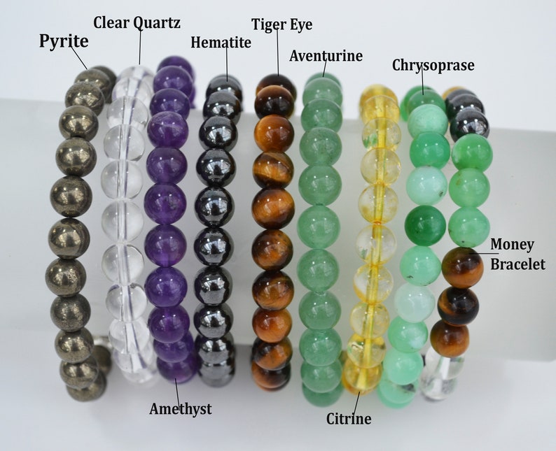 May include: A collection of beaded bracelets featuring various gemstones, including pyrite, clear quartz, amethyst, hematite, tiger eye, aventurine, citrine, and chrysoprase. The bracelets are labeled with the names of the stones. The last bracelet is labeled "Money Bracelet".