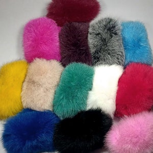 May include: Assortment of 14 faux fur pom poms in various colors, including pink, blue, red, white, black, yellow, and green.