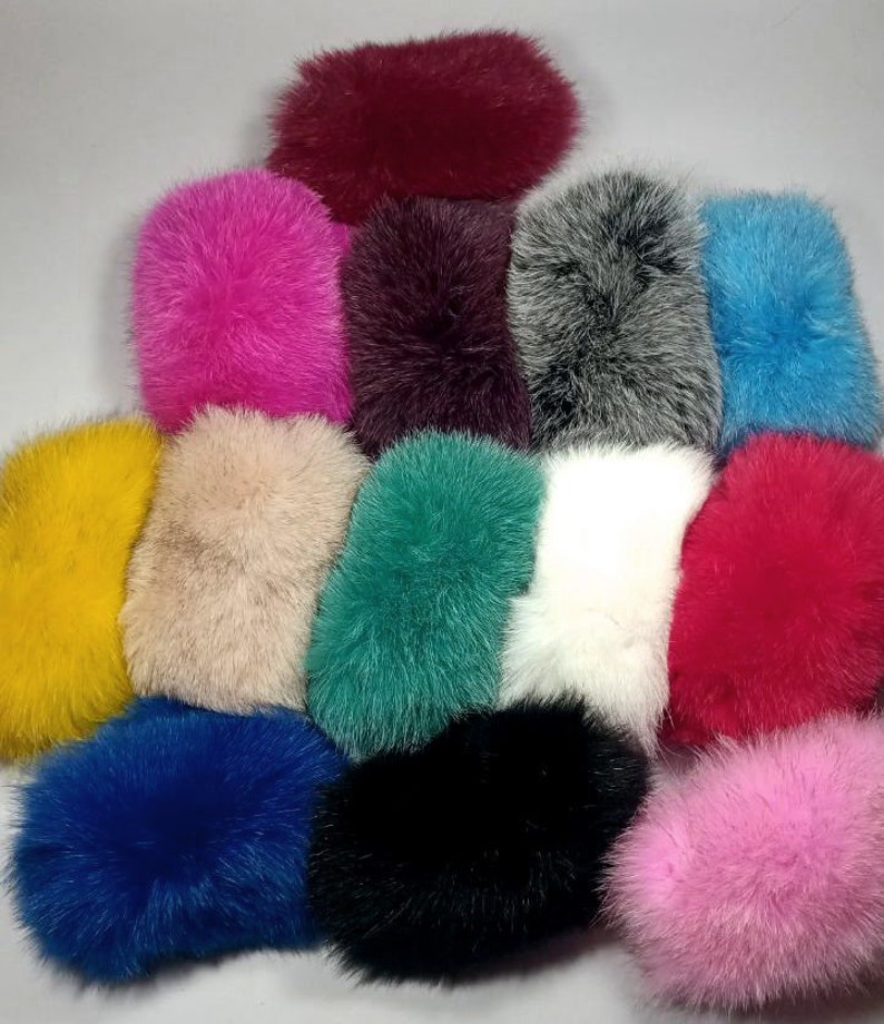 May include: Assortment of 14 faux fur pom poms in various colors, including pink, blue, red, white, black, yellow, and green.