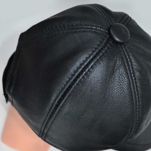 Puede incluir: Una gorra de b&eacute;isbol de cuero negro con un bot&oacute;n en la parte posterior.
