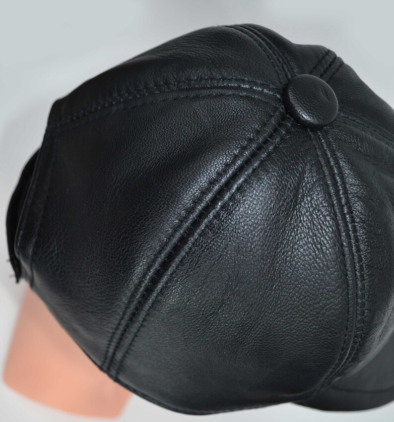 Puede incluir: Una gorra de b&eacute;isbol de cuero negro con un bot&oacute;n en la parte posterior.
