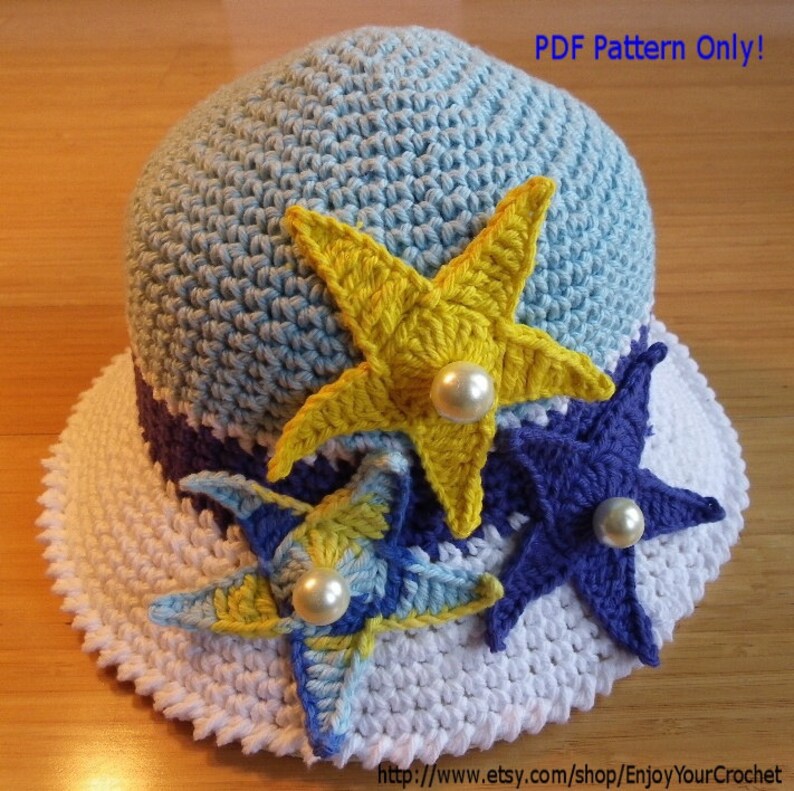 May include: A crochet hat with a white brim and a blue crown. The hat is decorated with three crocheted starfish in yellow, blue, and purple.