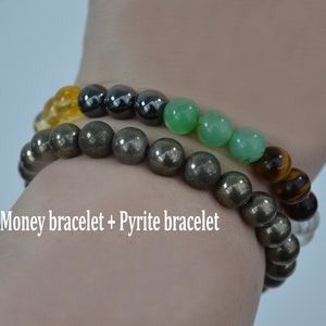 May include: Two beaded bracelets. One bracelet features pyrite beads, the other has a mix of citrine, hematite, green aventurine, and tiger's eye beads. The text on the image reads "Money bracelet + Pyrite bracelet."